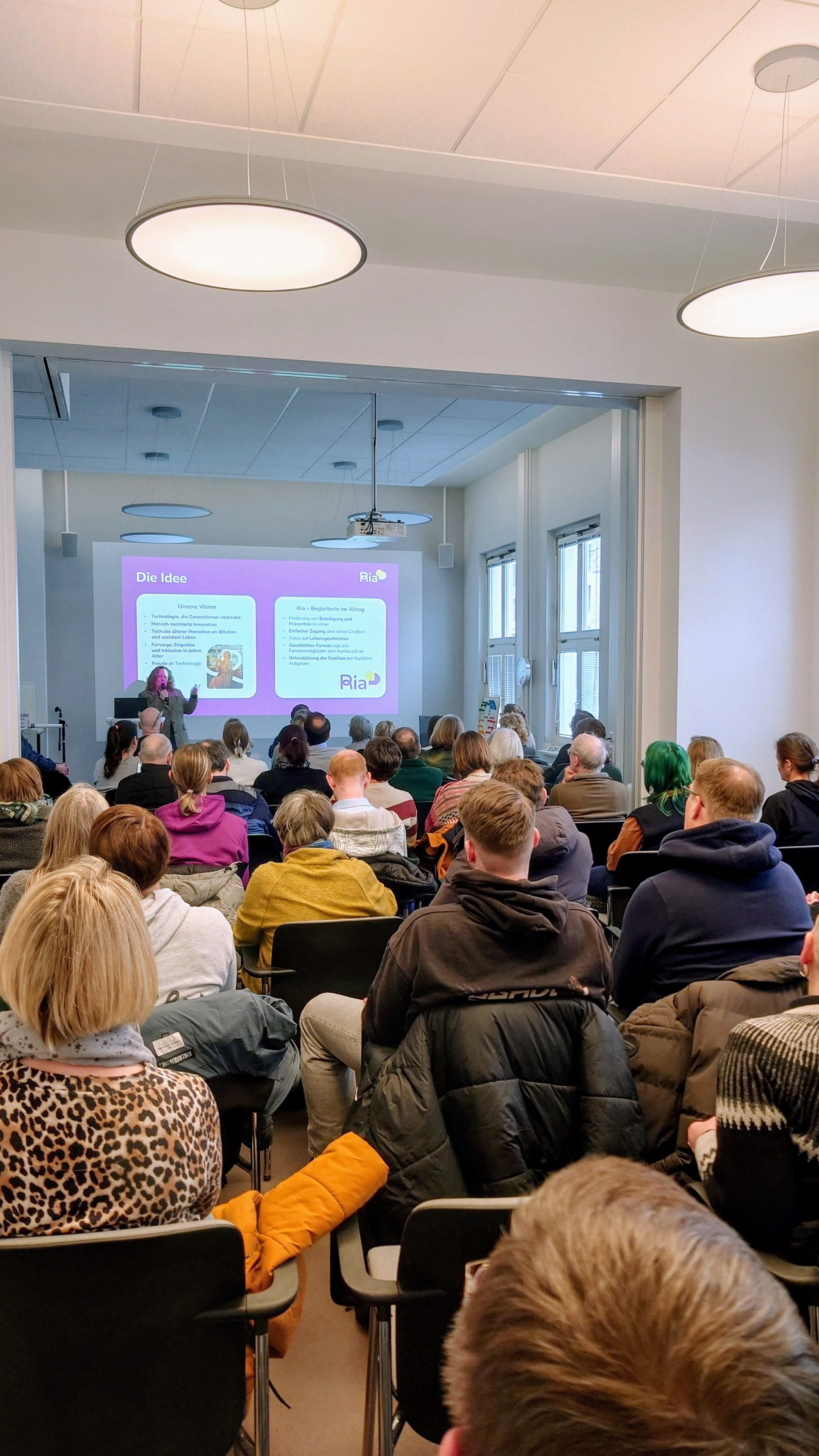 Referentin hält vor Zuschauenden den Vortrag