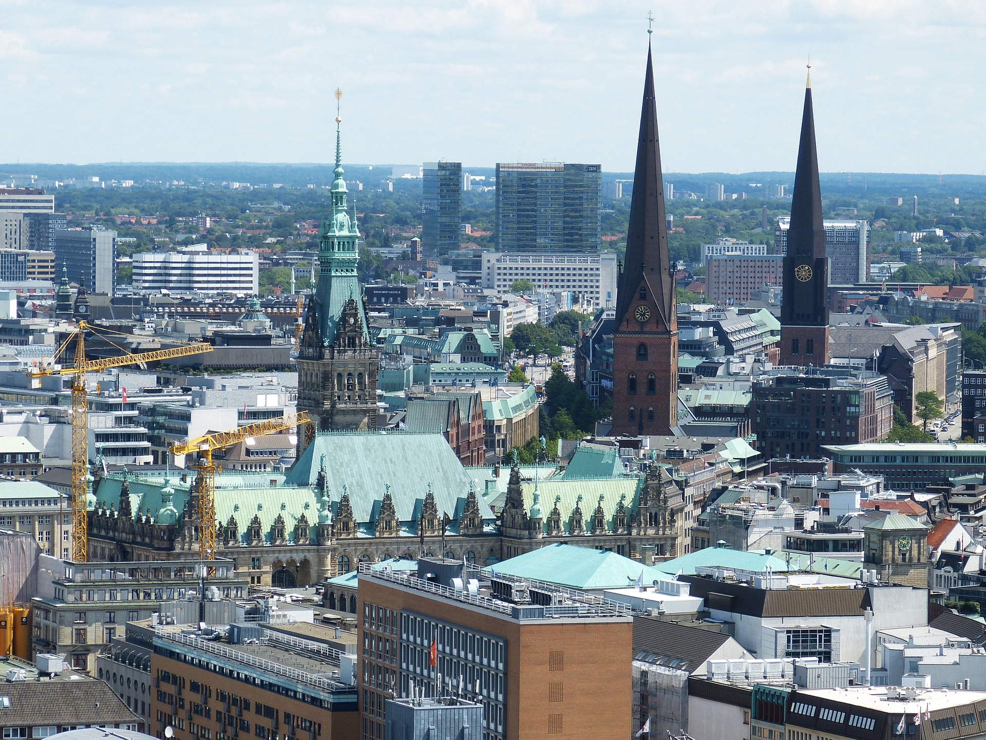 Hamburg von oben. Das Bild zeigt die Innenstadt mit Rathaus, Kirchtürmen sowie Einkaufs- und Bürogebäuden.