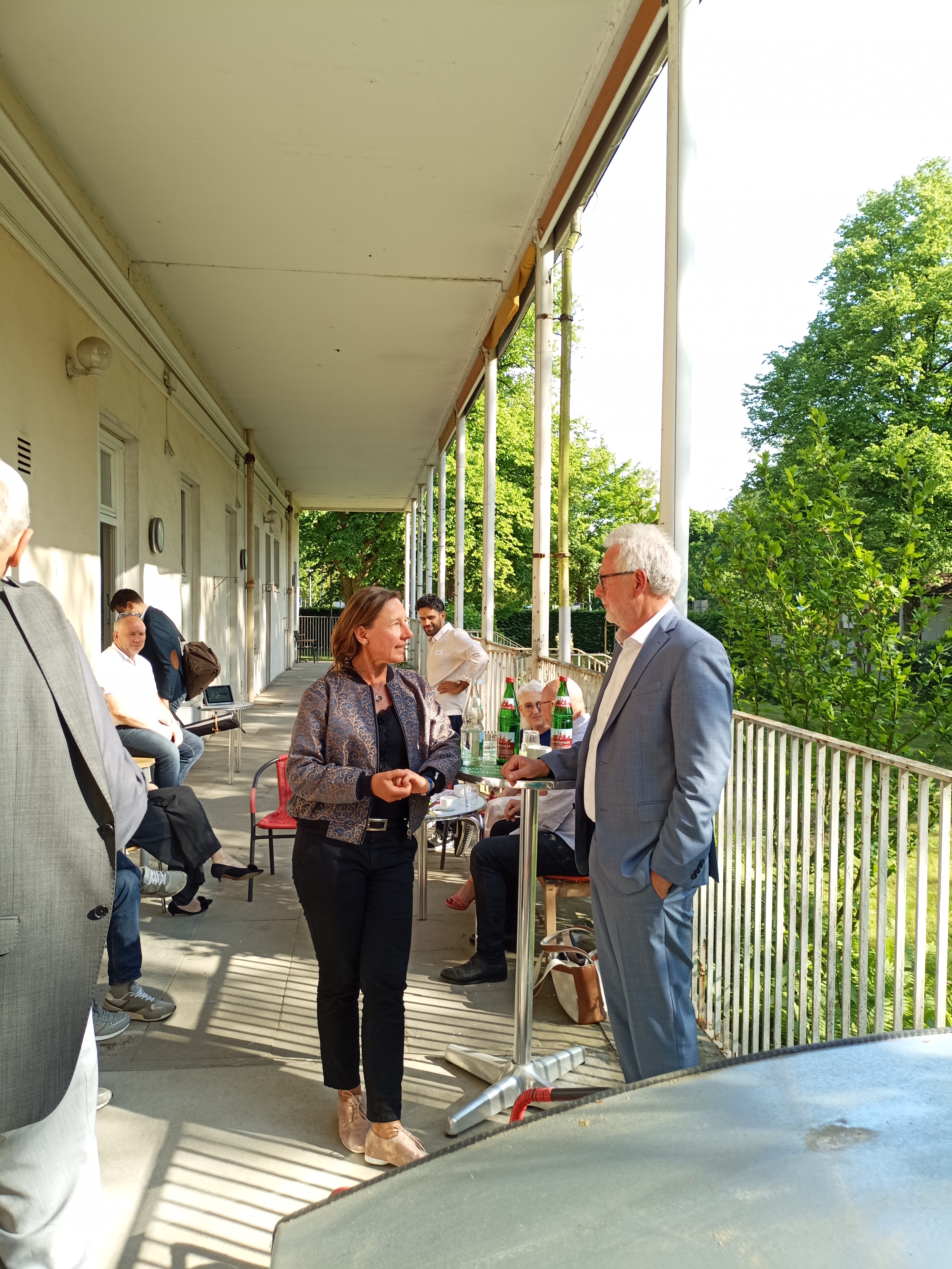 Teilnehmer einer Projektveranstaltung unterhalten sich auf der Terrasse des Hauses für Barrierefreiheit.