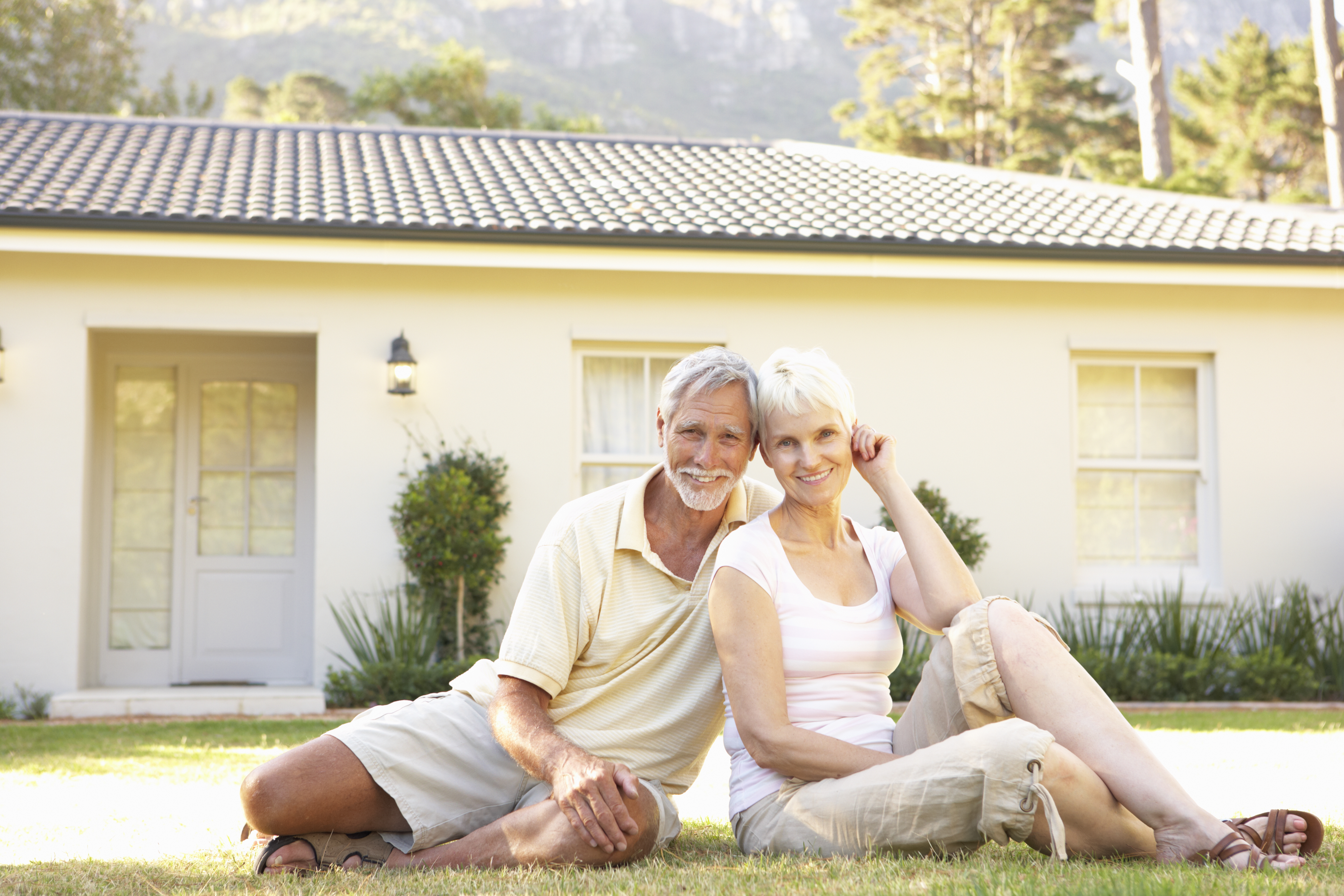Das Symbolbild zeigt ein älteres Ehepaar vor einem Einfamilienhaus.