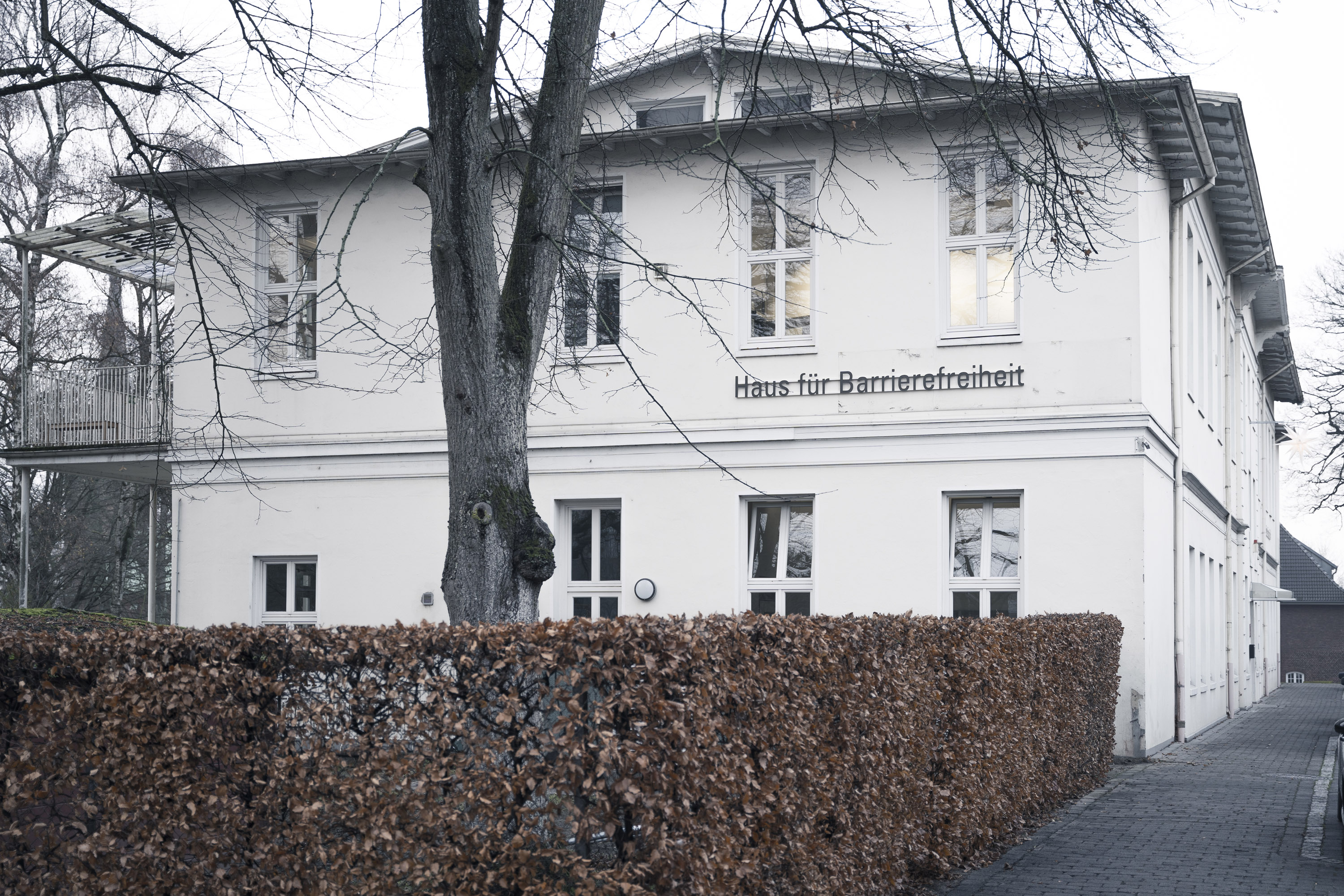 Das Bild zeigt die Seitenansicht vom Haus für Barrierefreiheit und den davor befindlichen Baum.